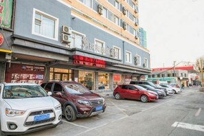 Eine Reihe geparkter Autos vor einem Gebäude mit mehreren Geschäften, darunter ein Restaurant mit sichtbarem Schild.