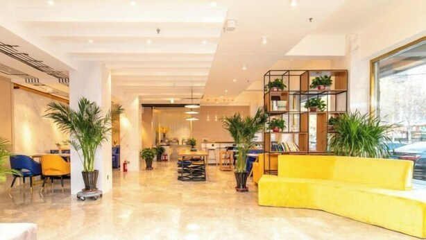 A modern lobby with a yellow sofa, potted plants, and a bright, well-lit interior. - Chonpines Hotel (Shengyang Provincial Government, Changjiang North Street, Beilin) (Shenyang)