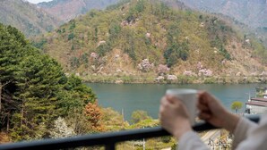 A view of a lake surrounded by mountains with trees and a building in the background. - Gapyeong Reflex Pool Villa Pension (Gapyeong)