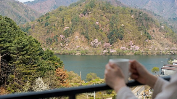 A view of a lake surrounded by mountains with trees and a building in the background. - Gapyeong Reflex Pool Villa Pension (Gapyeong)