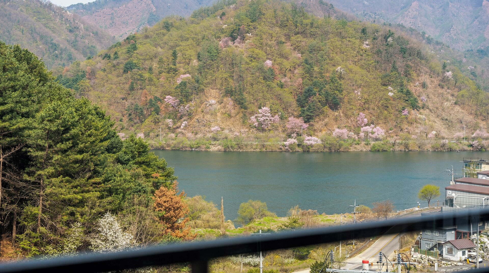 Un lago rodeado de montañas, árboles y un pequeño edificio al frente.