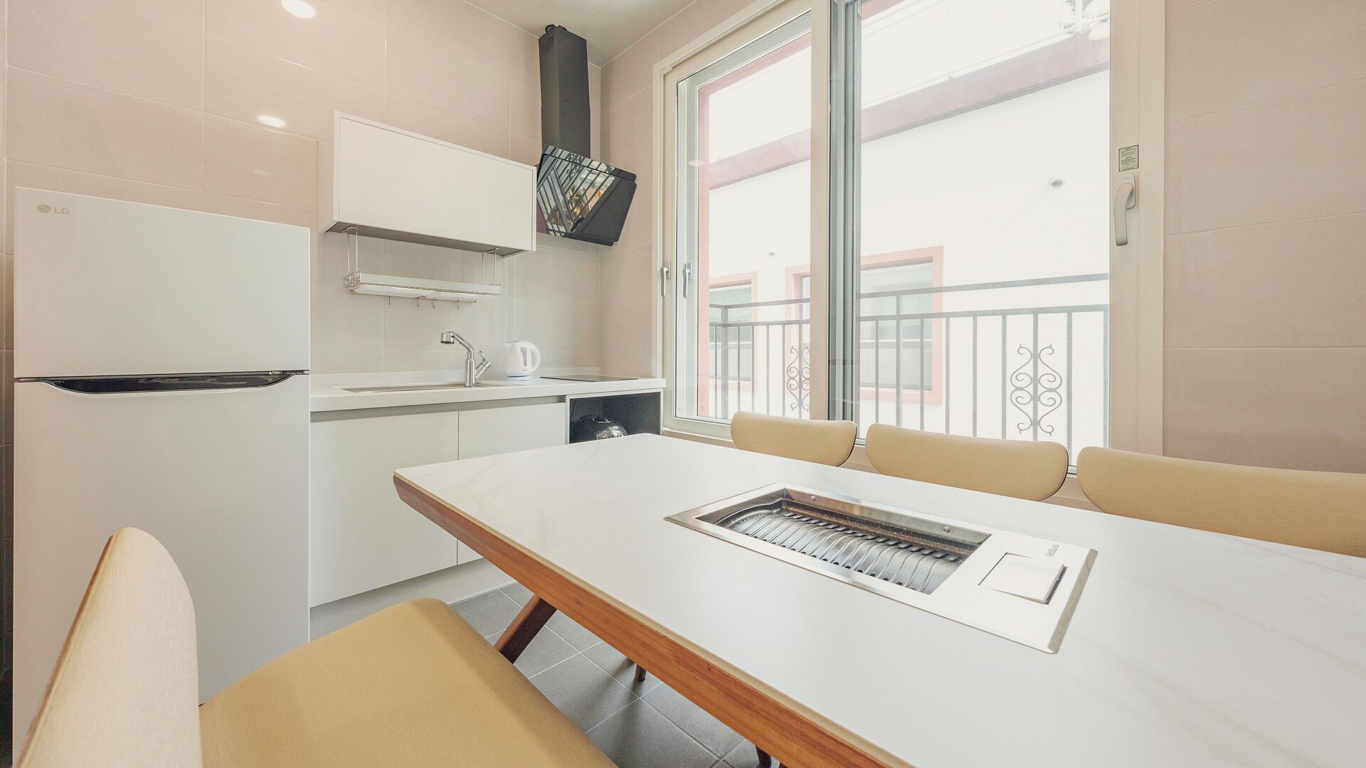 A modern kitchen with a built-in oven, a sink, and a window with a balcony view.
