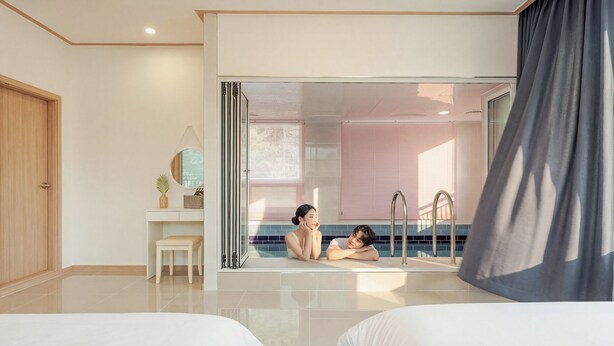 A modern hotel room with a large sliding glass door leading to a balcony, a bedside table with a lamp, and a large mirror. - Gapyeong Reflex Pool Villa Pension (Gapyeong)