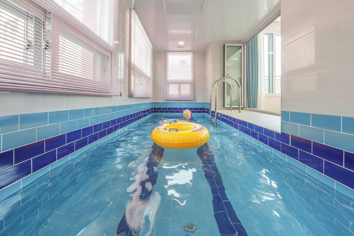 Una piscina interior con azulejos azules, un flotador amarillo y una vista despejada de toda su longitud.