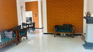 A spacious living area with a brick wall, a sofa set, a dining table, and a fireplace. - Eco Brick Transit villa  AC in Katunayake (Katunayake)