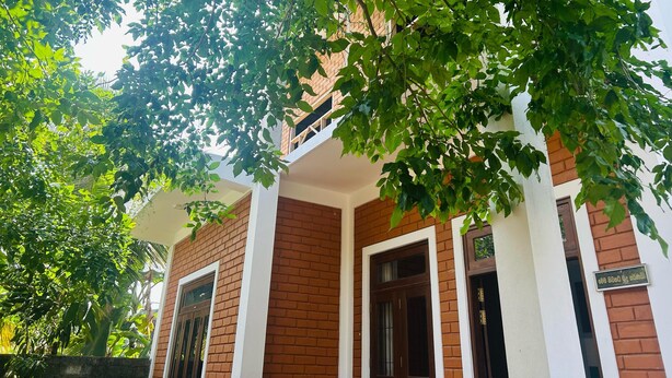 A building with a brick facade and white trim, featuring multiple windows and doors. - Eco Brick Transit villa  AC in Katunayake (Katunayake)