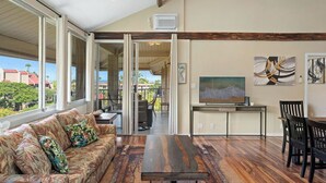 A spacious living area with a sofa, coffee table, and dining set. - Haleakala Shores B512: Luxe top-floor with dual master suites. Steps to beach. (Kihei)