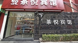 Un hôtel à thème, décoré autour du thé, avec une enseigne rouge bien visible et une façade en marbre noir.