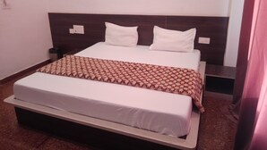 Ein ordentlich bezogenes Bett mit einem gemusterten Überwurf, zwei weißen Kissen und einem hölzernen Kopfteil.