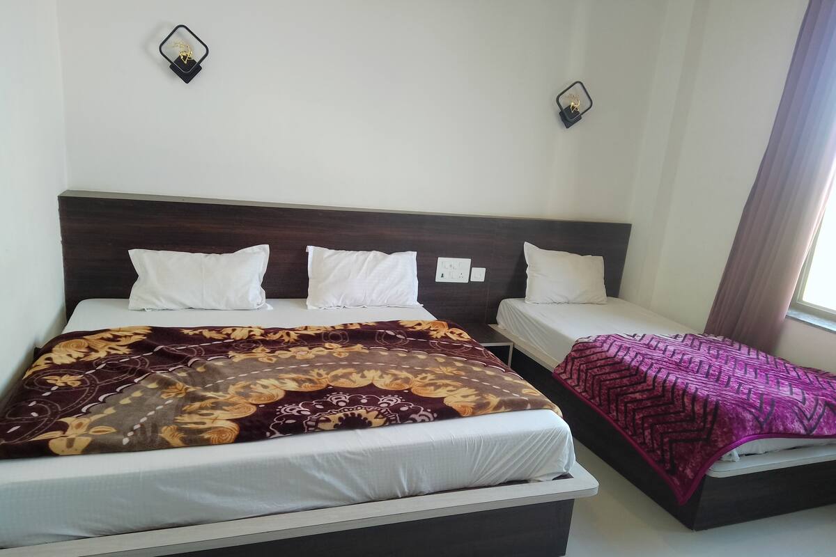 Een tweepersoonsbed met een bedspread met dessin en een eenpersoonsbed met een effen beddekleed.