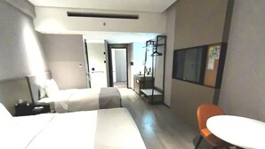 Ein modernes Hotelzimmer mit einem großen Bett, einem Schreibtisch, einem Sessel und einem kleinen Tisch.