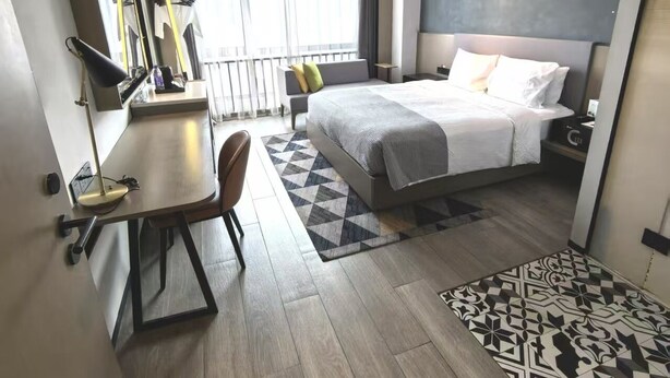 Ein modernes Hotelzimmer mit Bett, Schreibtisch, Stuhl und einem großen Fenster.