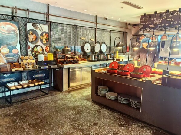 A modern kitchen area with stainless steel appliances, a coffee station, and a display of plates and bowls. - Wanda Yue Shanghai (Shanghai)
