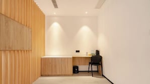 A modern, minimalistic room with a wooden slat wall, a desk with a chair, and a small cabinet. - Changee Hotel MINI (Shanghai Pudong Jinqiao Road Subway Station) (Shanghai)