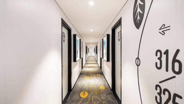 A hotel hallway with a long corridor, numbered doors, and a decorative carpet with leaf patterns. - Changee Hotel MINI (Shanghai Pudong Jinqiao Road Subway Station) (Shanghai)