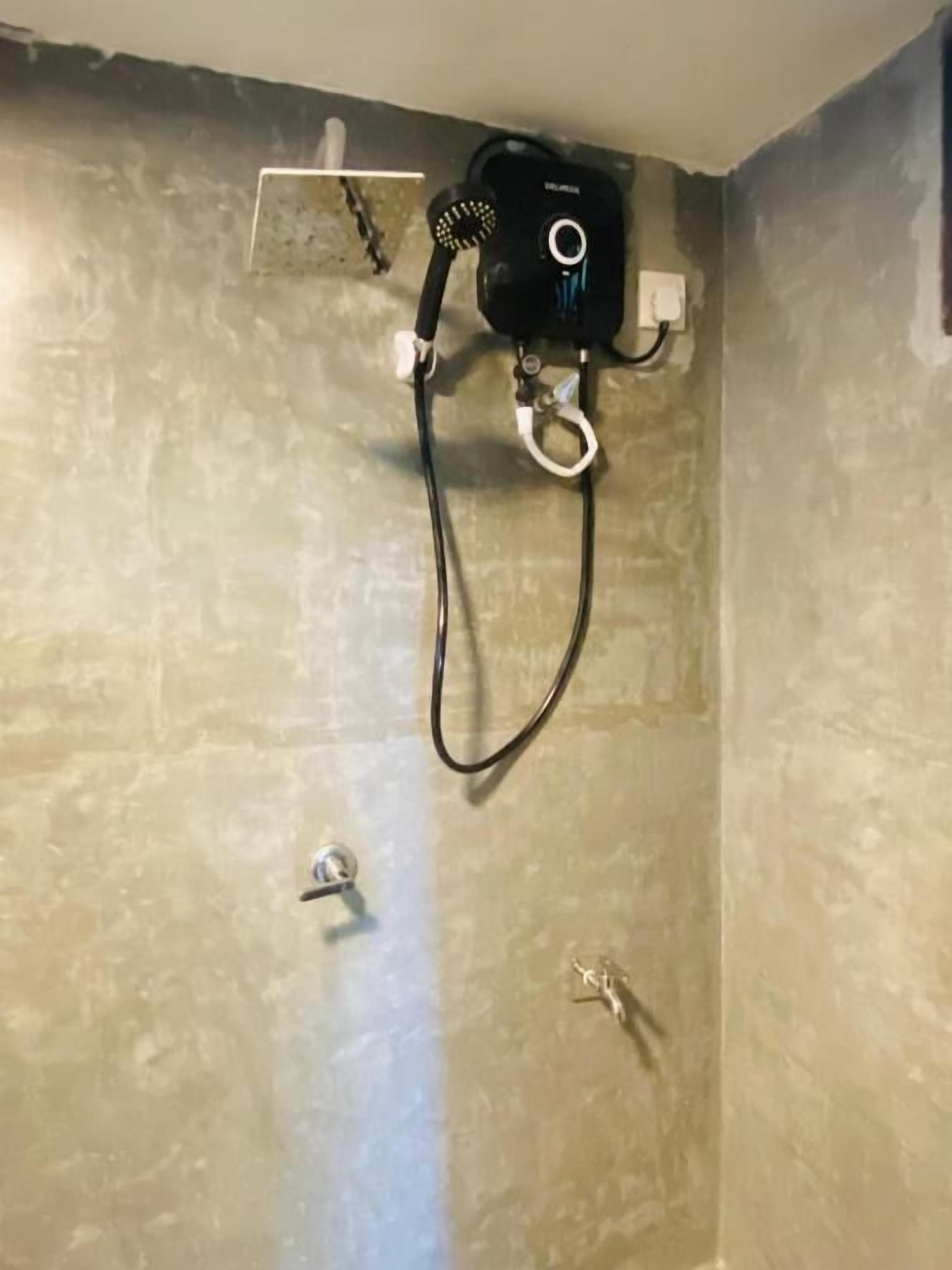 A bathroom with a shower, a towel rack, and a wall-mounted heater.