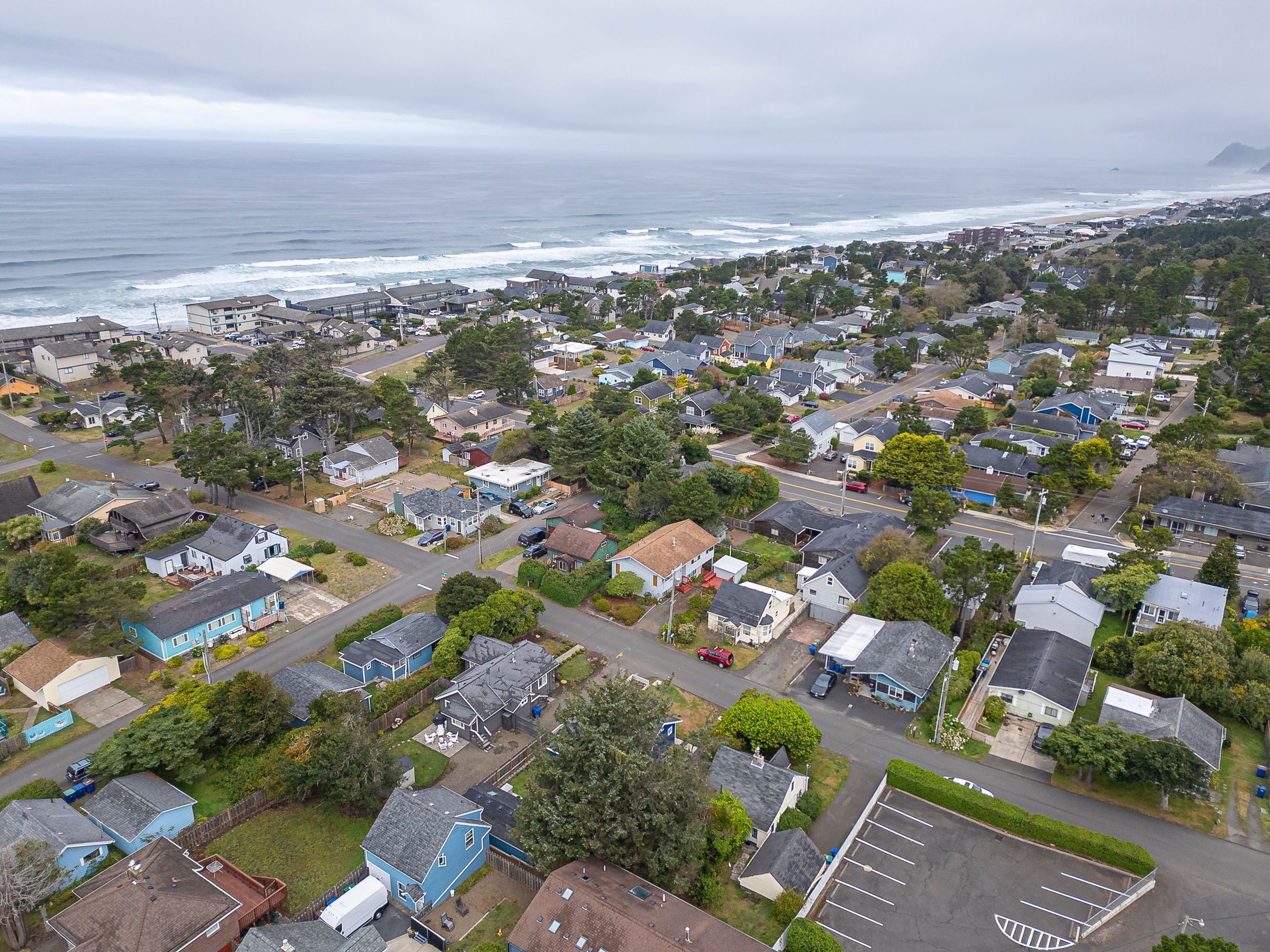 An aerial view of a coastal residential area with houses, streets, and a beach.