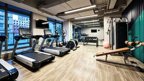 Et fitnesscenter med løbebånd, crosstrainere og styrkeudstyr.