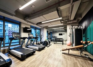 Et fitnesscenter med løbebånd, crosstrainere og styrkeudstyr.