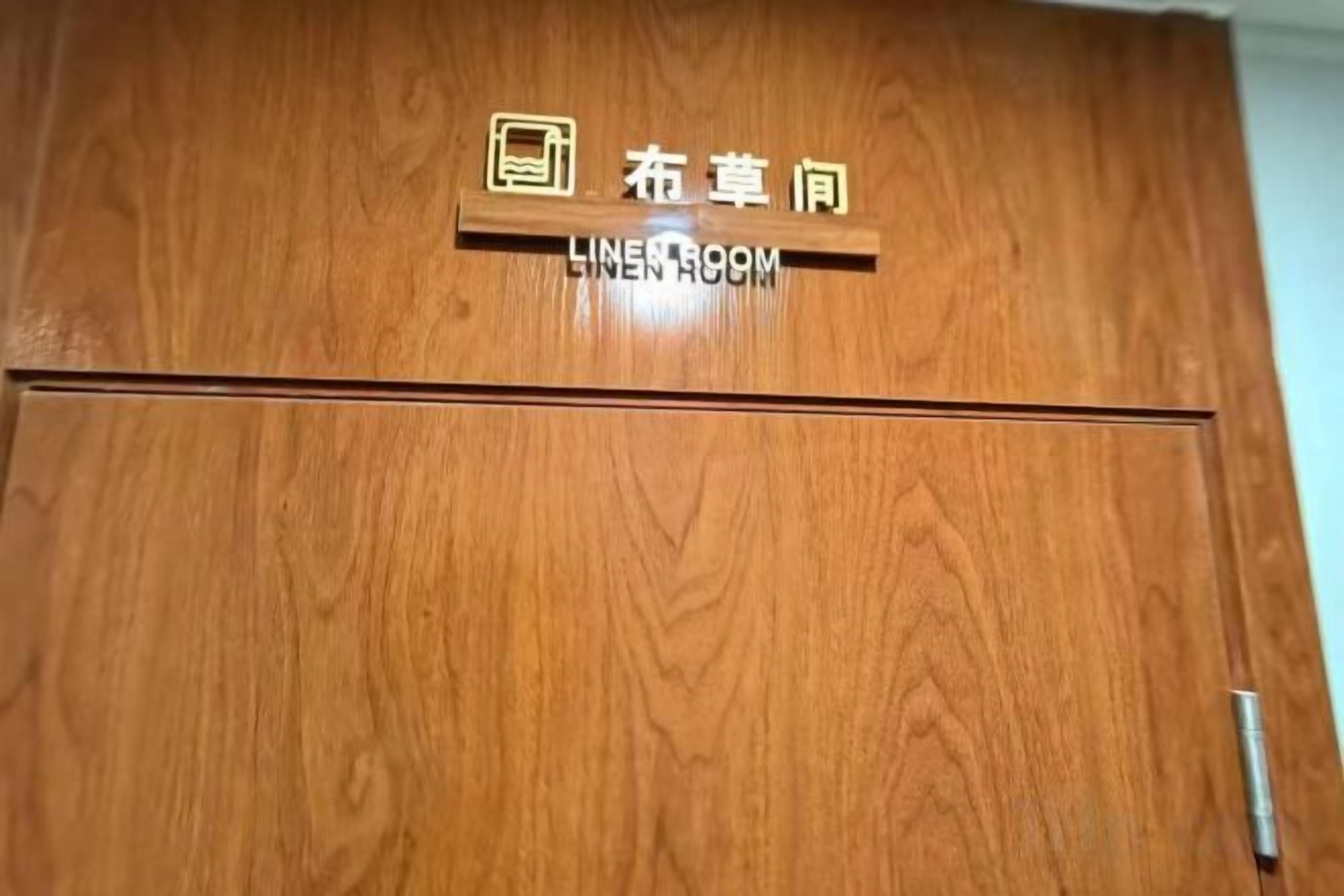 Una puerta de madera con un letrero que indica 'LINENROOM' y un símbolo que representa un baño.