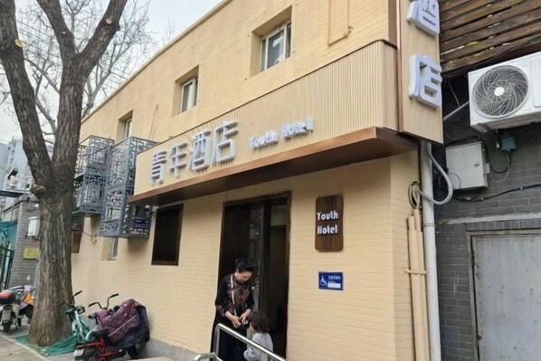 A Youth Hotel with a signboard, a tree, and a parked bicycle. - Youth Hotel (Beijing Temple of Heaven West Gate) (Beijing)