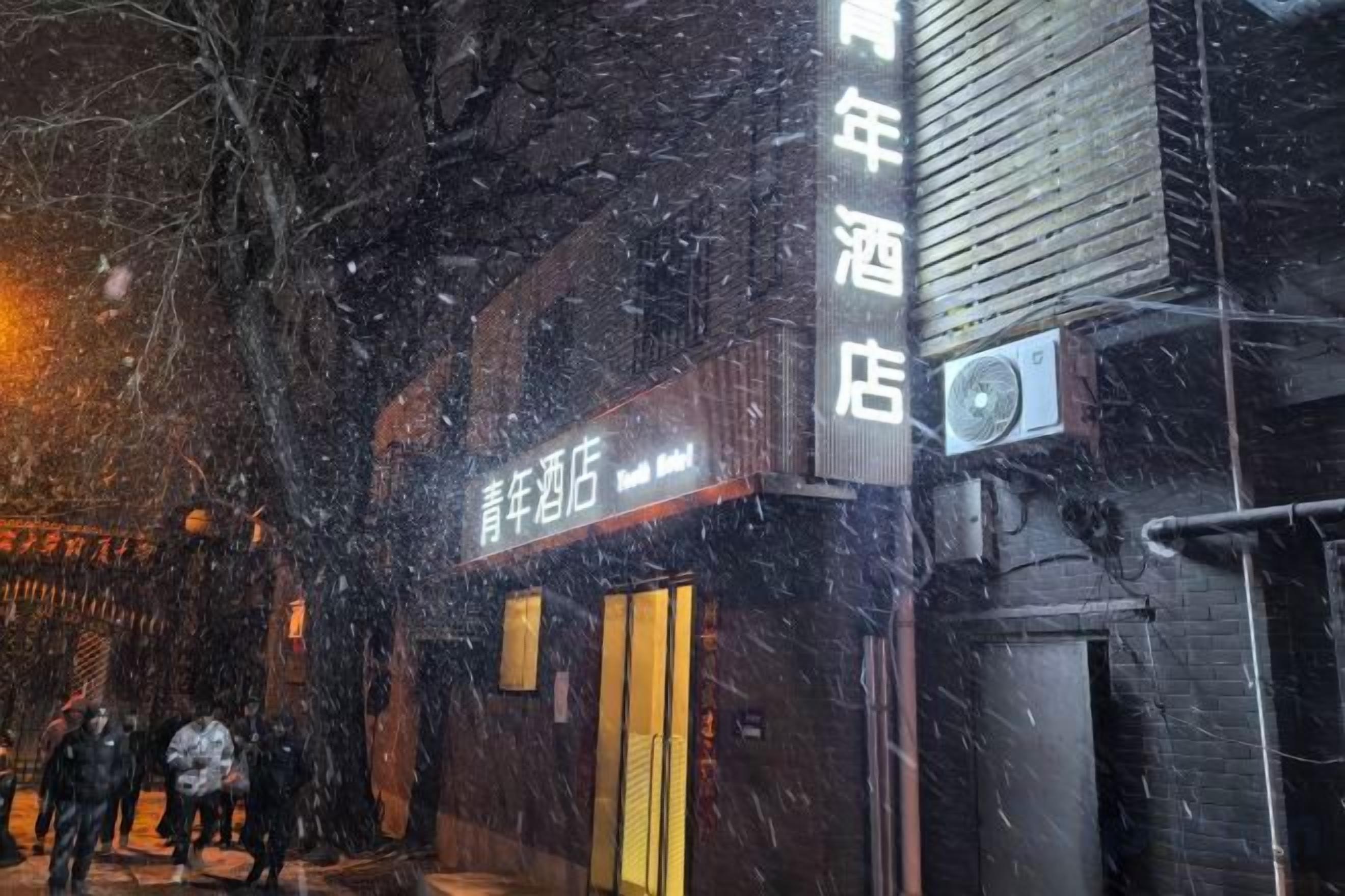 A building with a sign that reads '青年酒店' and a visible air conditioning unit.