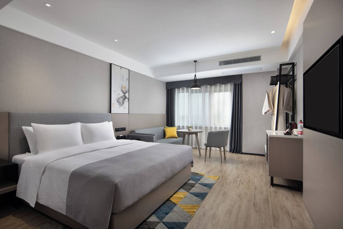 Een moderne hotelkamer met een groot bed, een bureau, een stoel en een klein tafeltje.