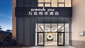 Een hotelentree met een modern ontwerp, met een grote glazen deur en een bord met Chinese karakters.