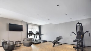 Een moderne sportschool thuis met loopbanden, een bankdrukrek en een Smith-machine.