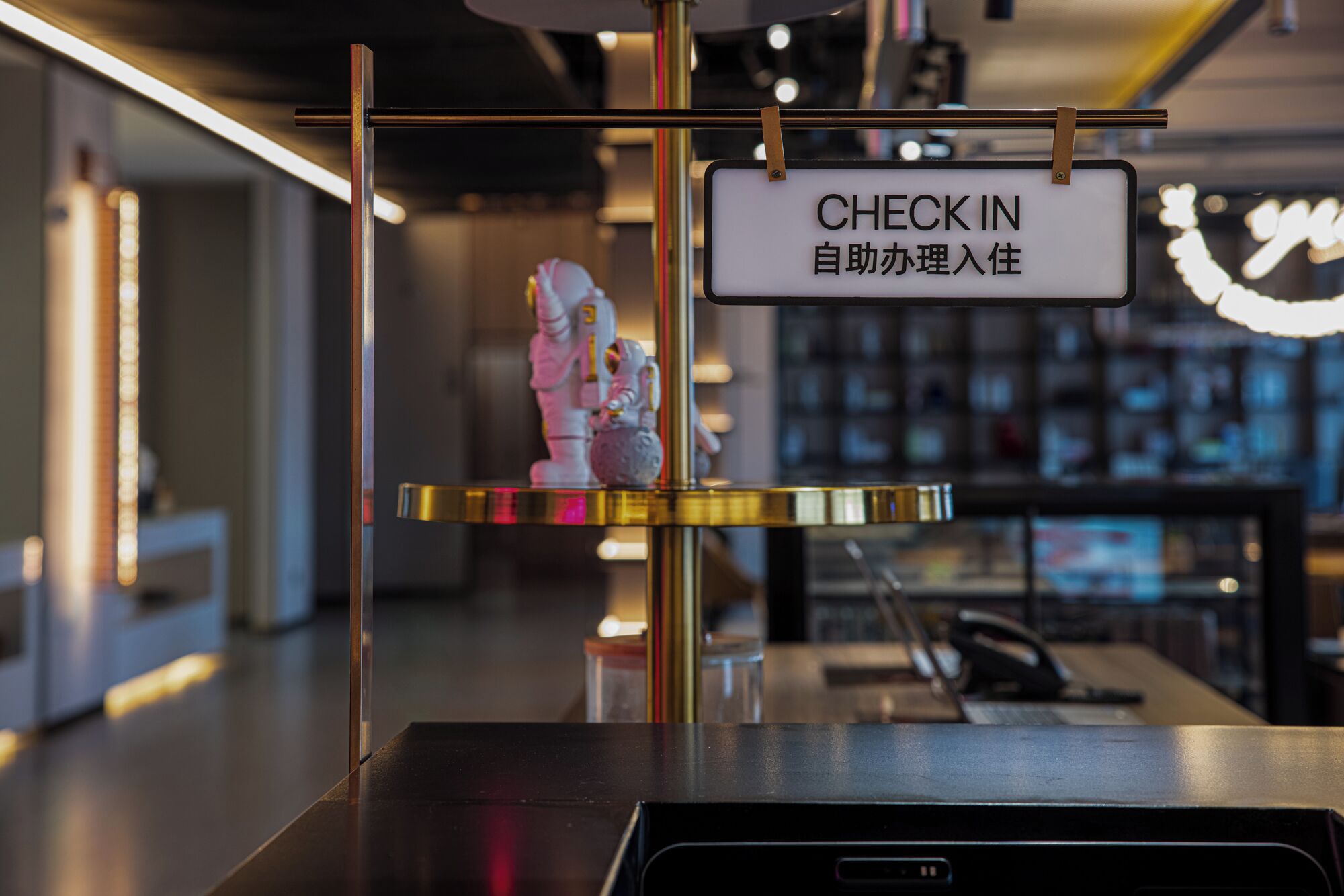 Un mostrador de recepción con un cartel que dice 'CHECK IN', una pequeña estatua y una vitrina de cristal.