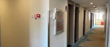 A hotel corridor with doors, a phone, and a fire alarm on the wall.