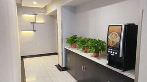 Een moderne hotellobby met een receptiebalie, plantenbakken en een digitale kiosk.