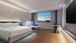 Une chambre d’hôtel moderne avec un grand lit, un bureau et une télévision.