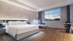 Une chambre d’hôtel moderne, dotée d’un grand lit, d’un bureau et offrant une vue sur le paysage urbain à travers la fenêtre.