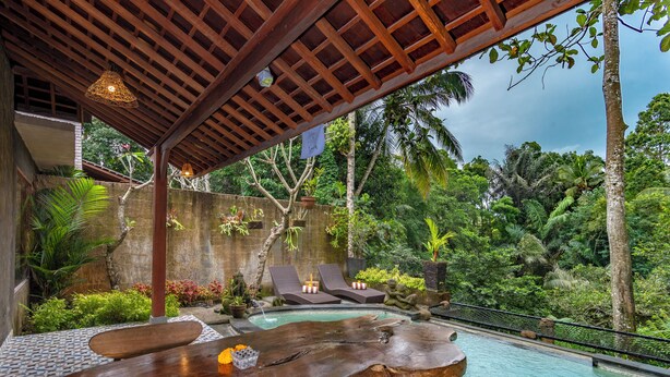 A wooden deck with a pool, lounge chairs, and a tropical garden. - Hoshi Jungle Resort by Dhananjaya Hospitality (Tegallalang)