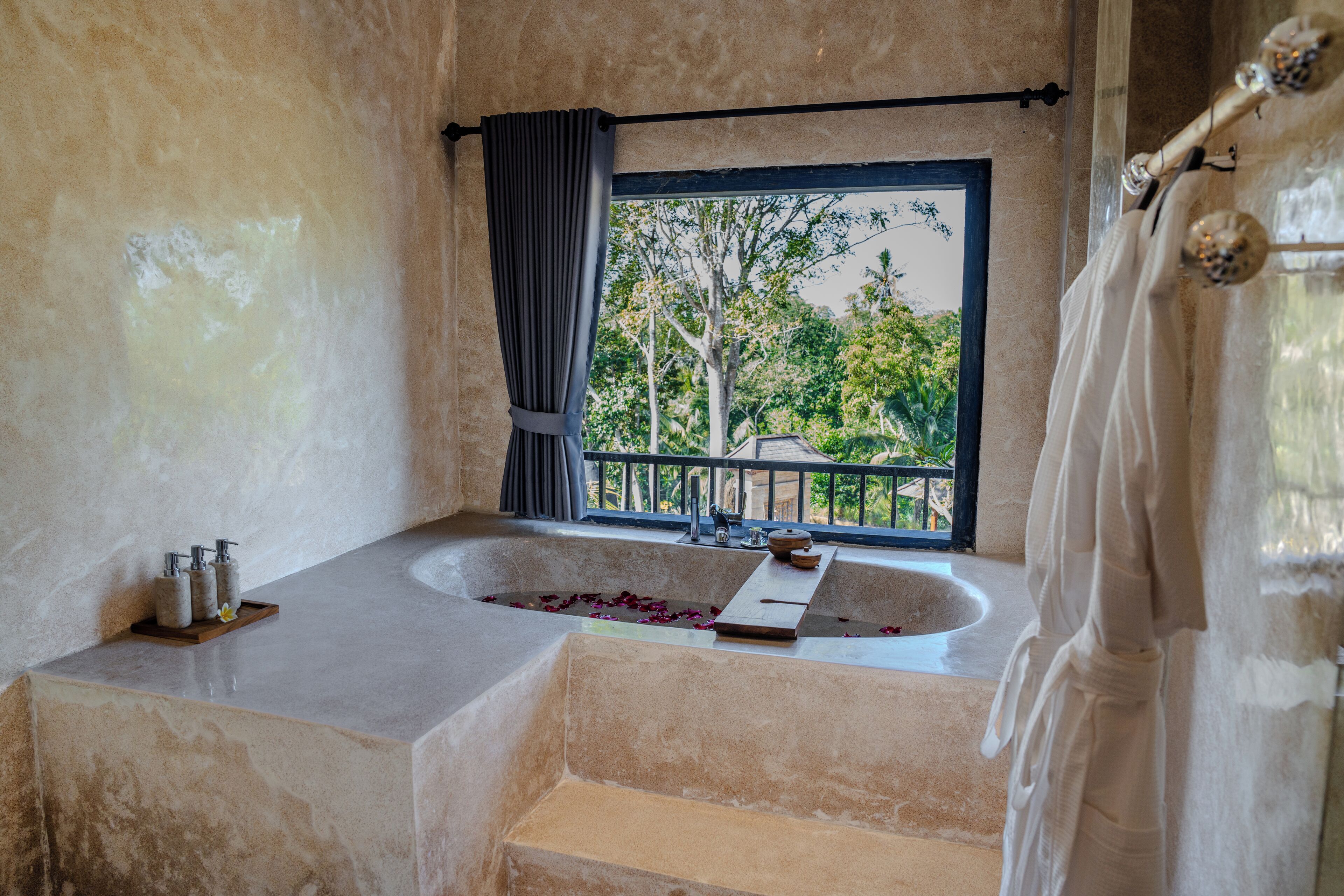 Un baño con bañera, ventana con vistas a árboles y cortina de ducha.