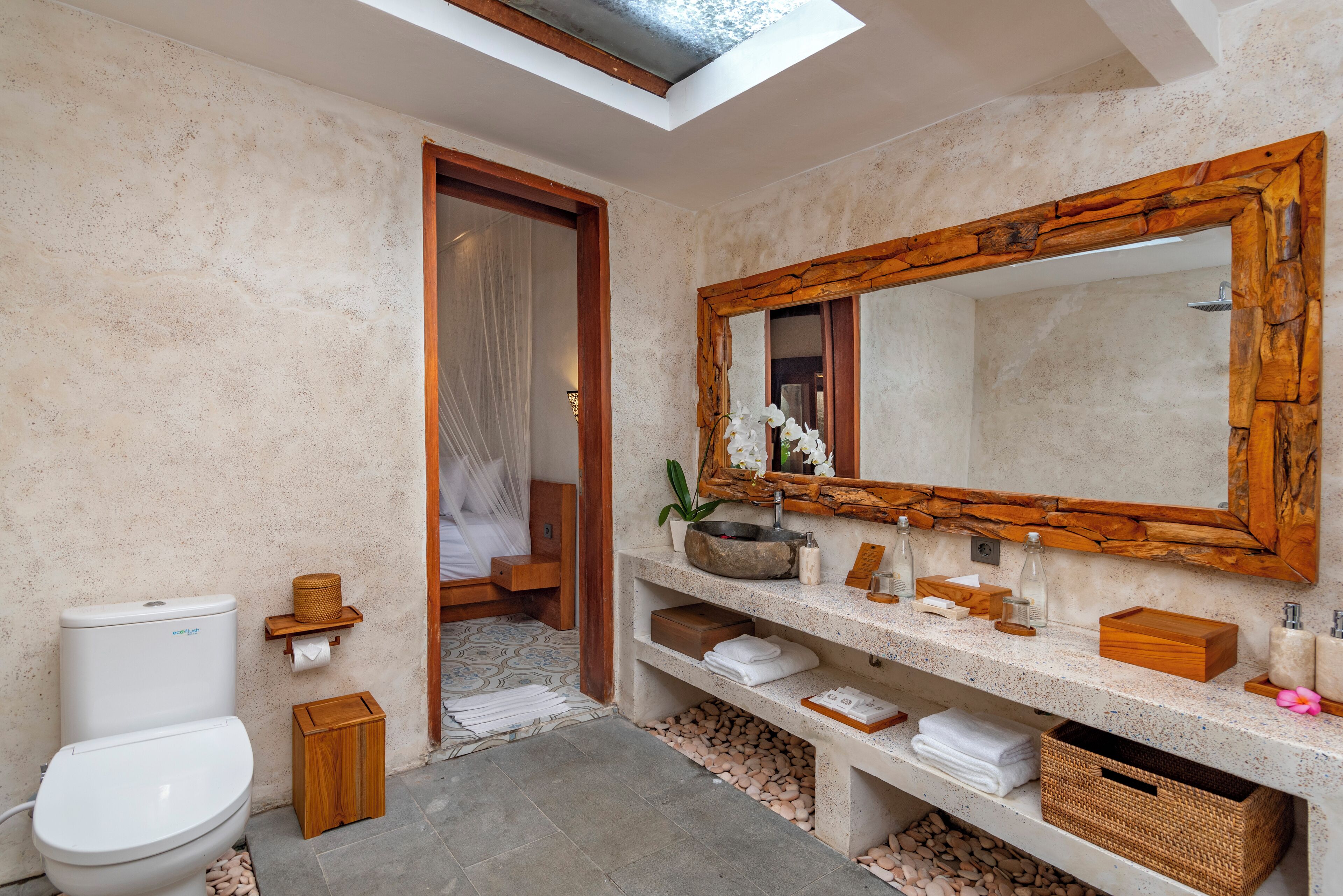 Une salle de bain moderne dotée d’un puits de lumière, d’un grand miroir et d’un lavabo en pierre.