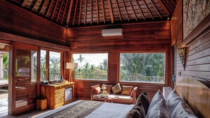 A wooden room with a bed, a desk, and a window overlooking greenery. - Hoshi Jungle Resort by Dhananjaya Hospitality (Tegallalang)