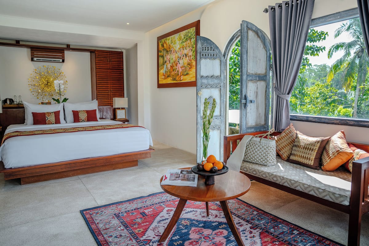 A bedroom with a bed, a sofa, a coffee table, and a window with curtains.