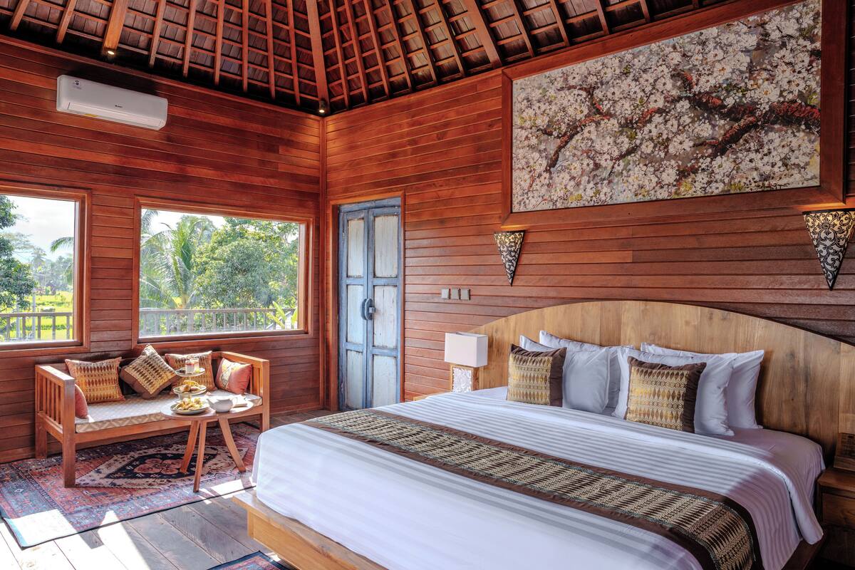 A wooden room with a bed, a bench, and a door.