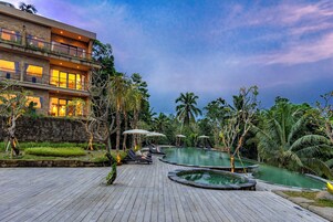 Un resort con zona de piscina, sillas de descanso y un edificio con varios balcones.