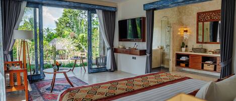 Um quarto espaçoso com uma cama grande, televisão, banheiro com chuveiro e varanda com vista para o exterior.