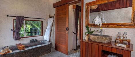 Une salle de bain avec un lavabo en pierre, un meuble-lavabo en bois et un grand miroir.