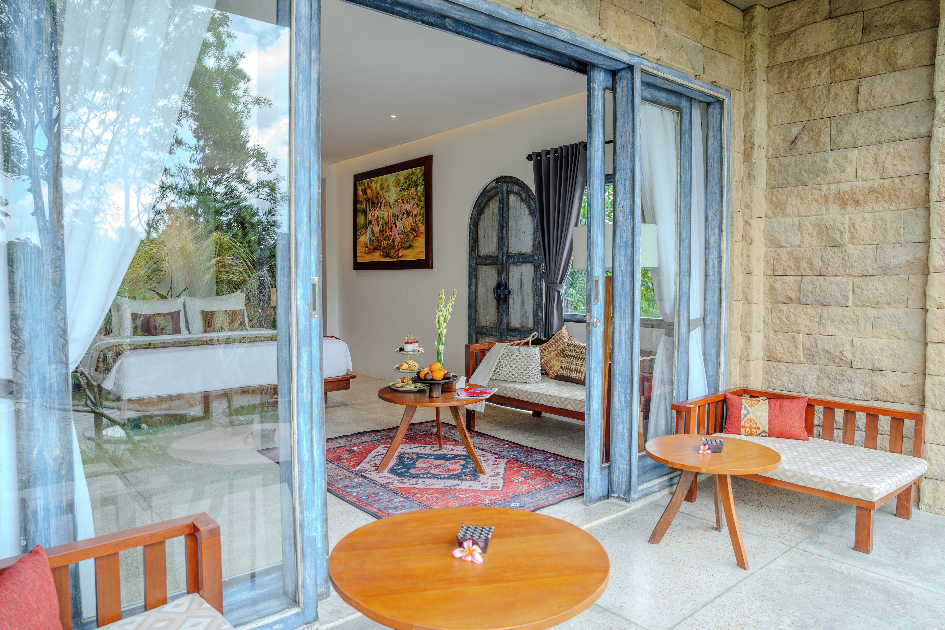A spacious living area with a sofa, two small tables, and a large window.