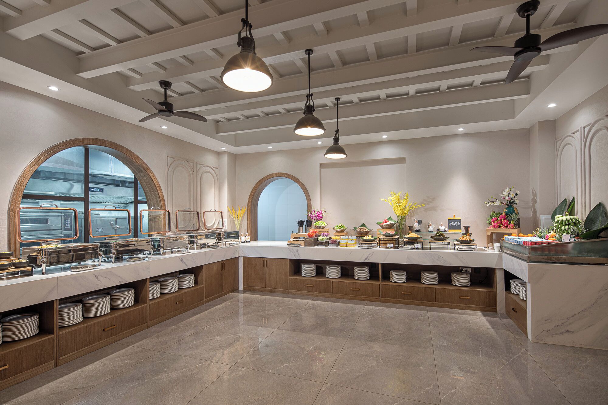A spacious kitchen with a marble countertop, multiple serving stations, and a high ceiling with exposed beams.