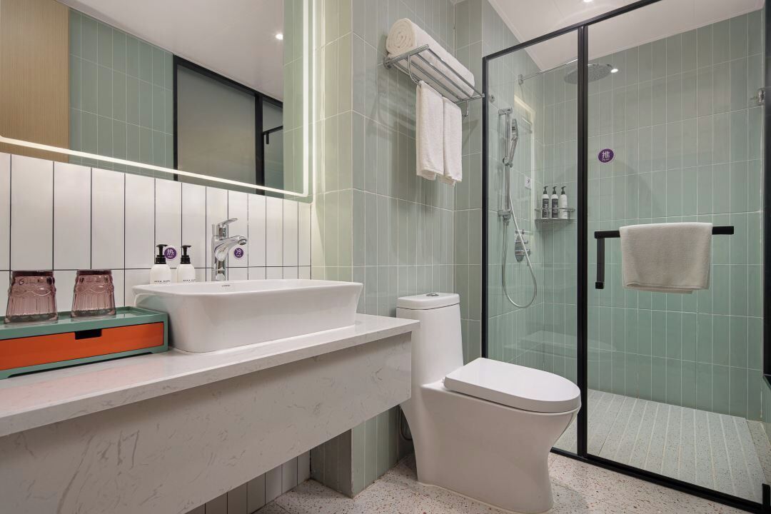 A modern bathroom with a glass shower enclosure, a white sink, and a toilet.