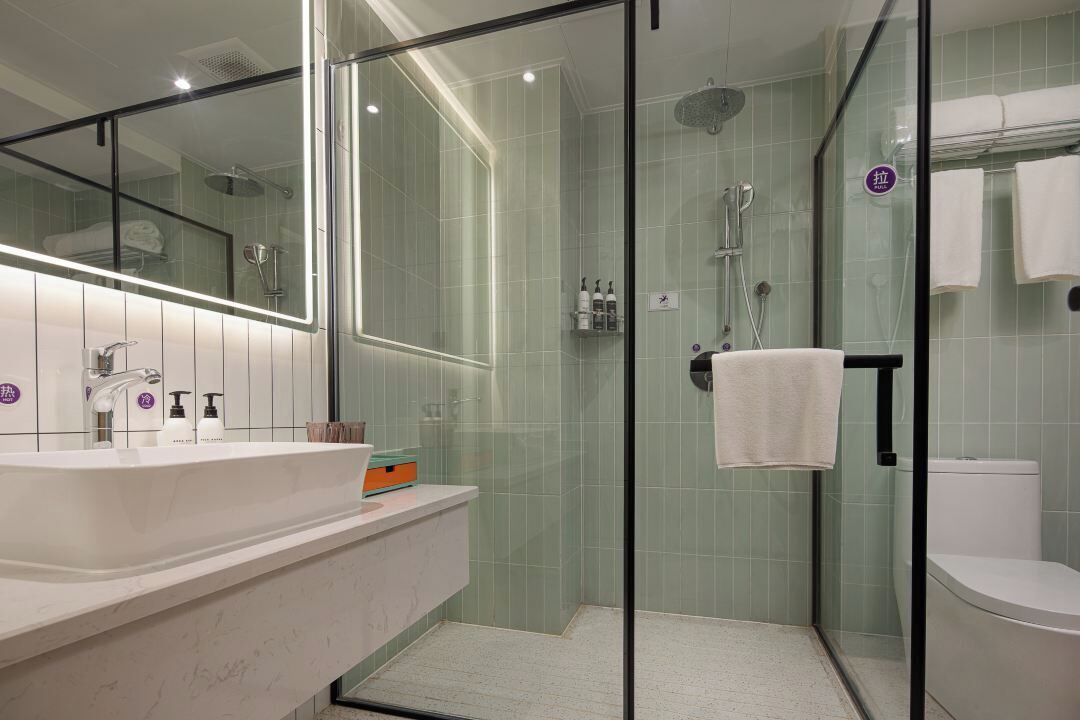 Une salle de bain moderne avec une douche à parois de verre, un lavabo blanc et un grand miroir.