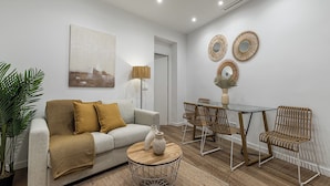 Un salon moderne comprenant un canapé, une table basse et un coin repas avec des chaises et une table en verre.