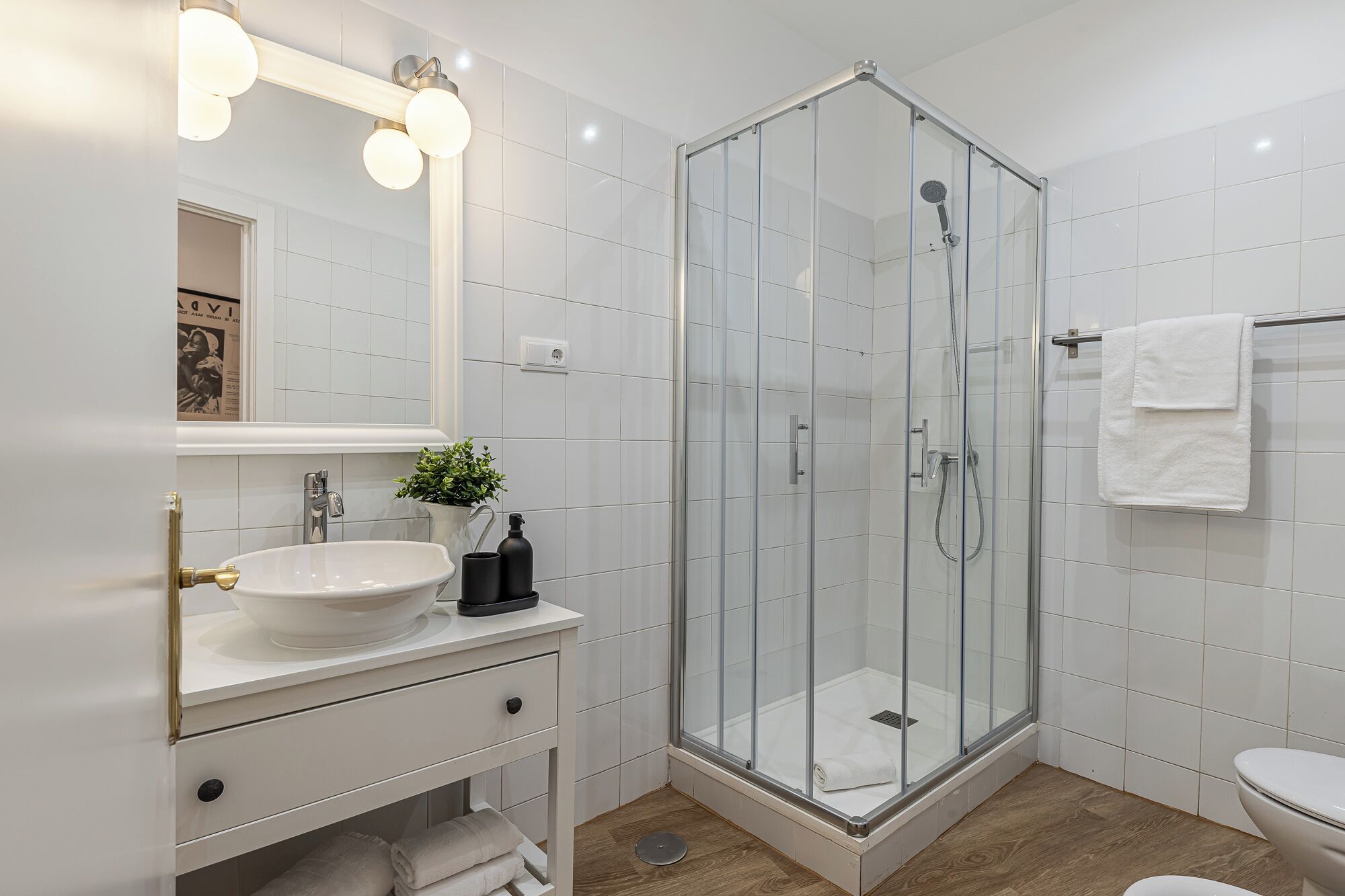 Ein modernes Badezimmer mit einer gläsernen Dusche, einem weißen Waschbecken und einem Spiegel über der Waschtischplatte.