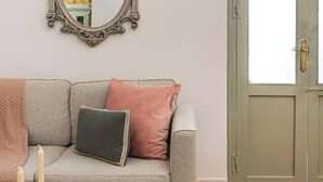 A living room with a grey sofa, a decorative mirror, and a green door. - Malasaña Gold (Madrid)